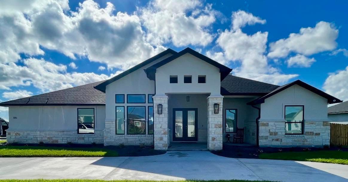 Newly built stucco-and-stone home in Portland, Texas with seamless gutters along the rooflines