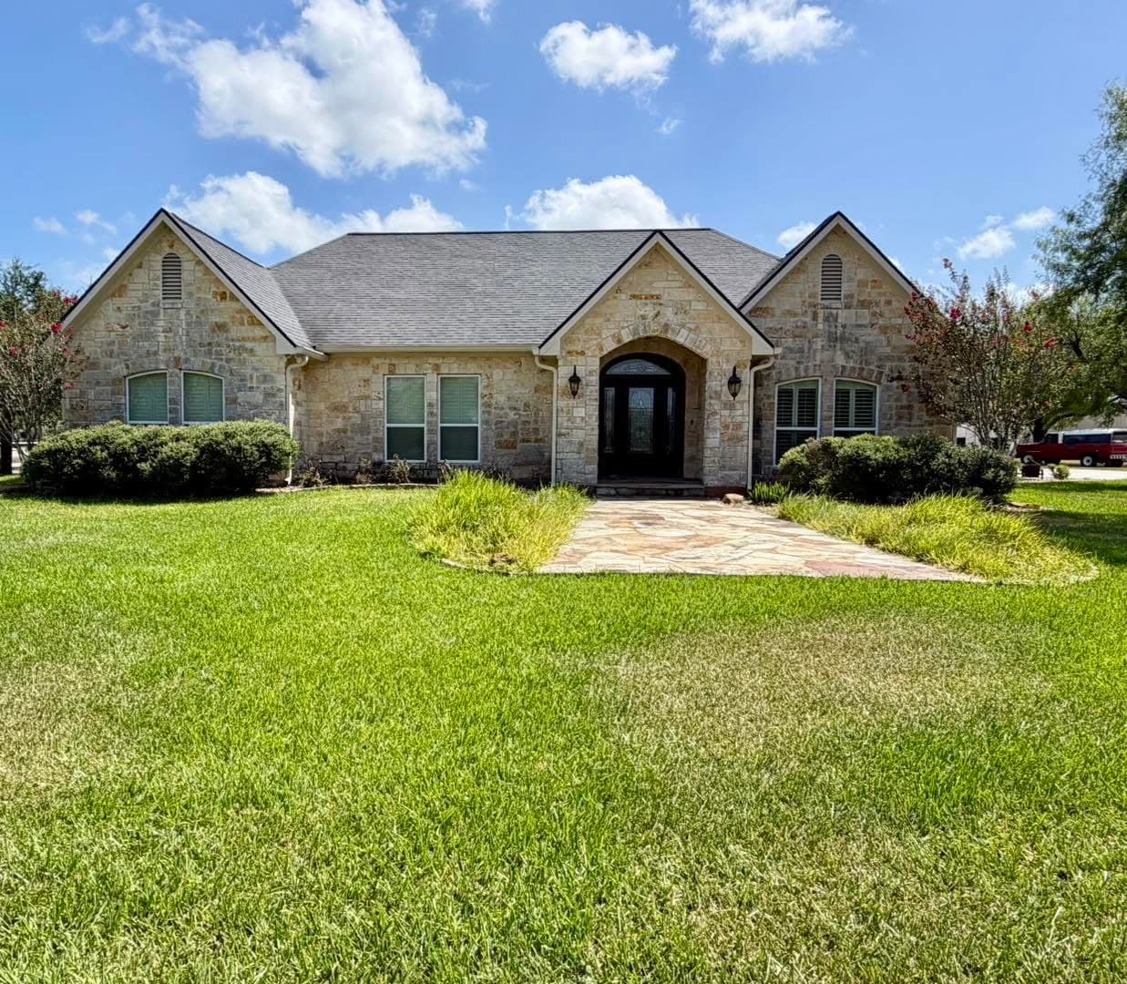 Stone-front home with an arched entry and seamless gutters along the eaves