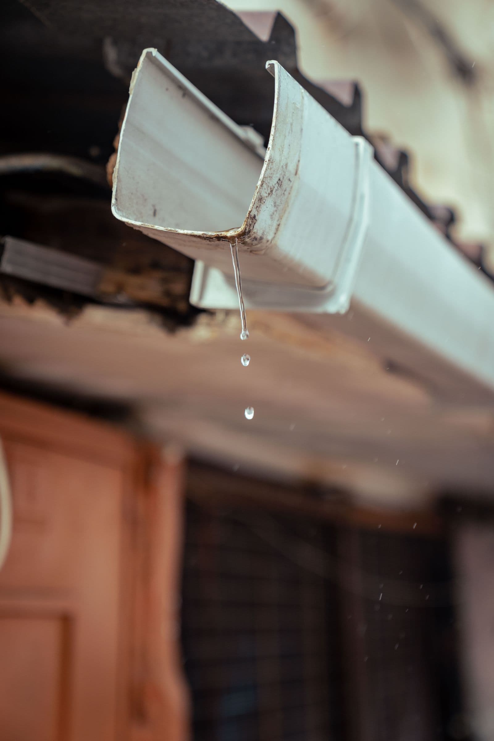 An aging, debris-worn gutter dripping water