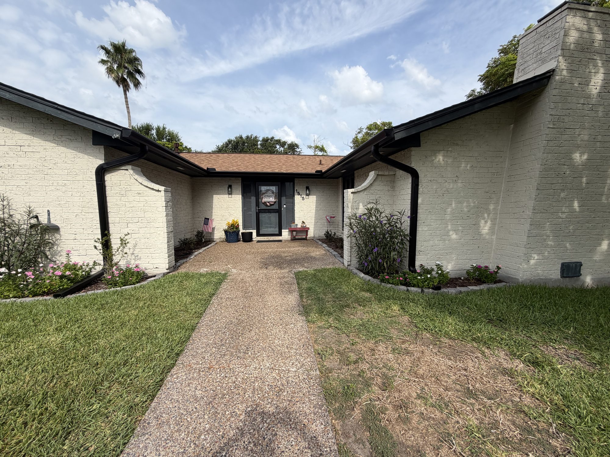Entry courtyard of a Portland, TX home with black seamless gutters and downspouts