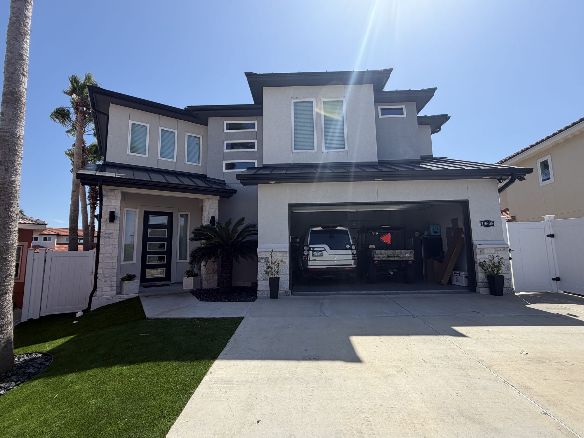 Two-story stucco house with palms and black seamless gutters in the Corpus Christi area