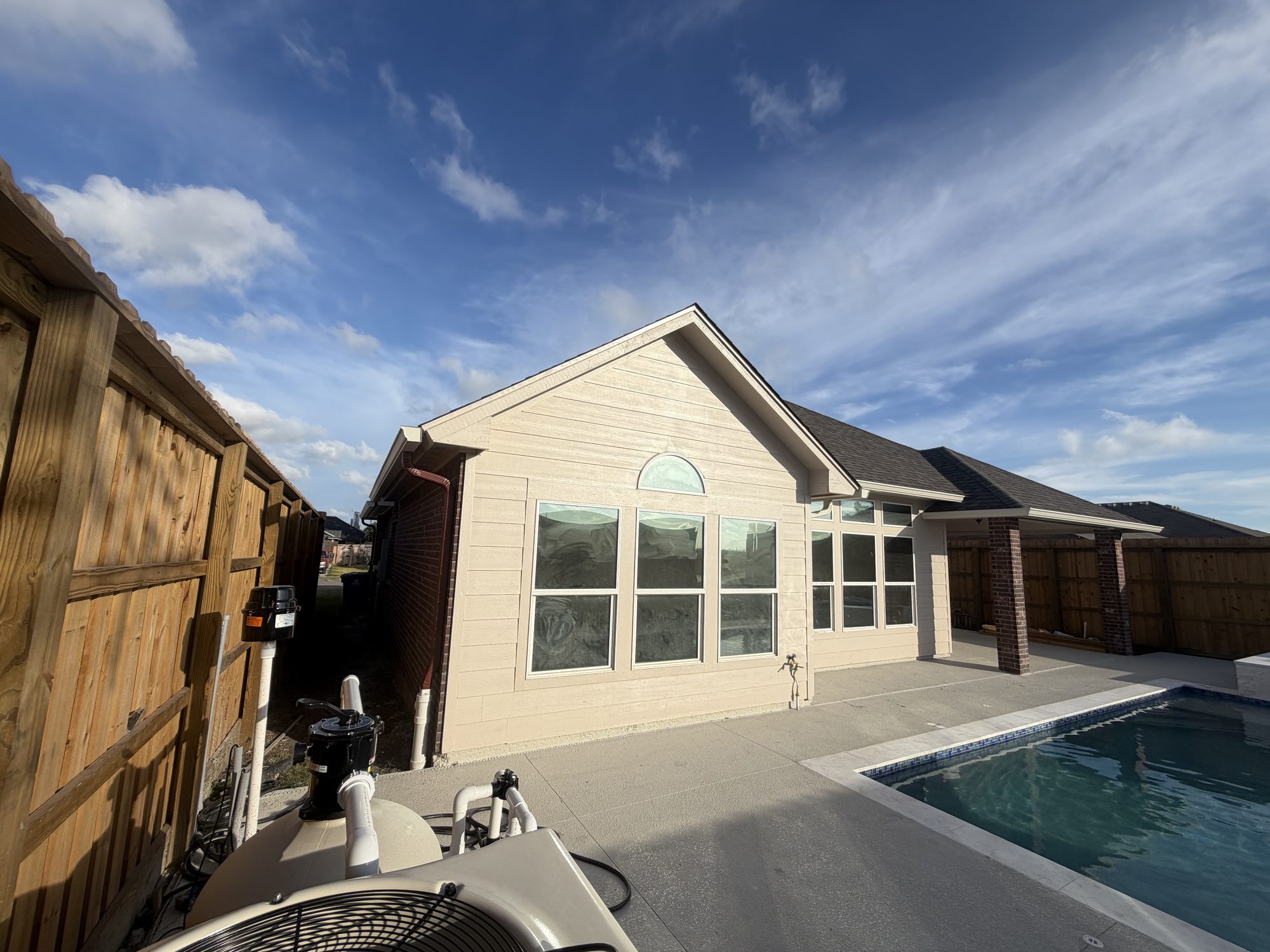 Cream siding and a pool patio with seamless gutters in Portland, TX