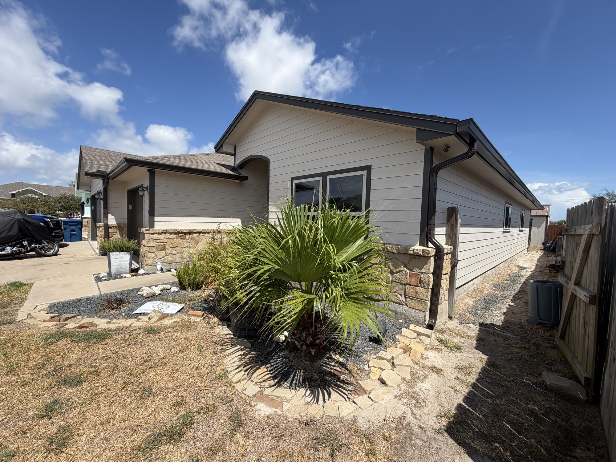 Cream siding, a palm, and a black downspout in the Corpus Christi area