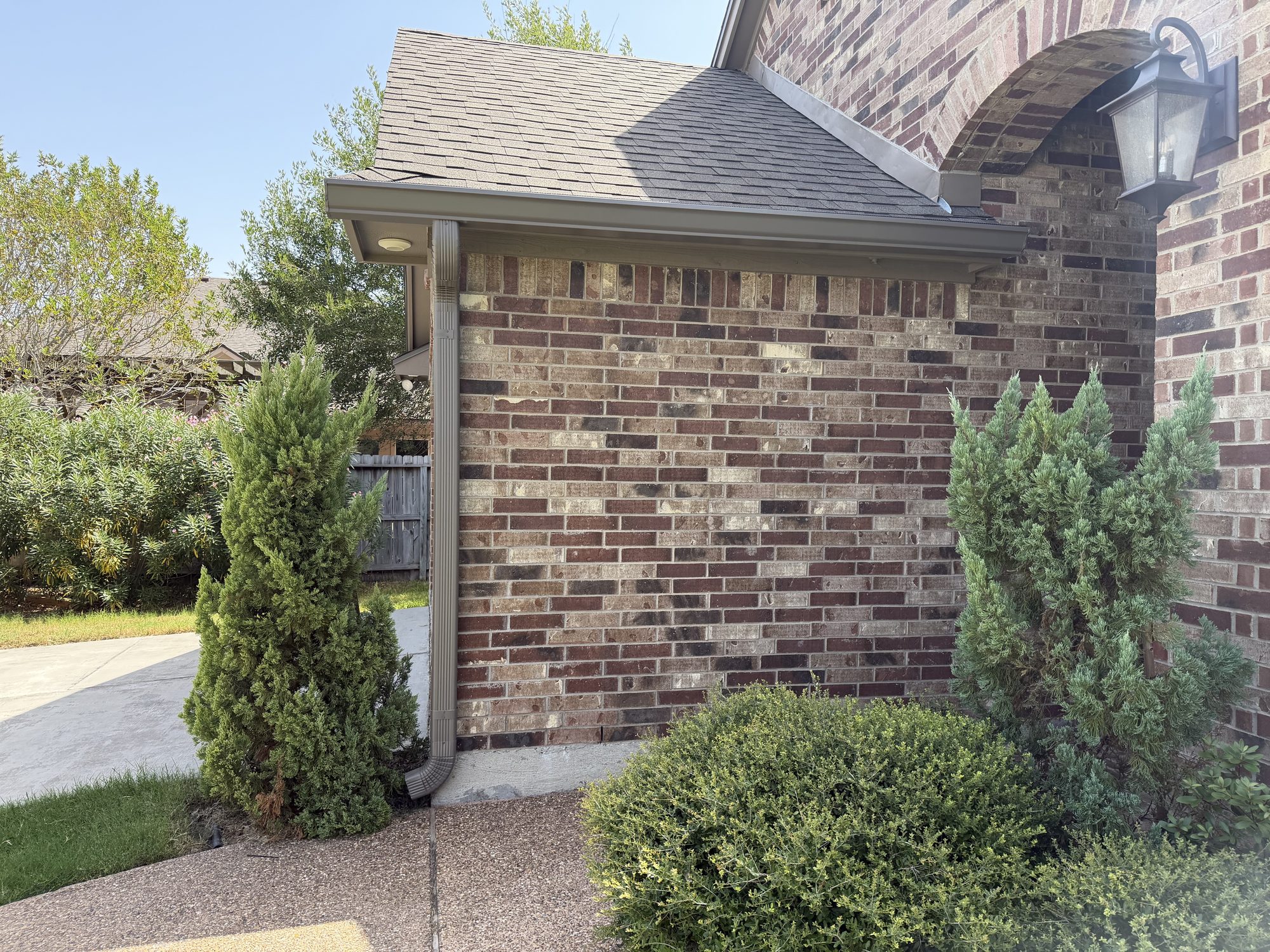 Brown seamless gutter end cap and downspout on brick in Portland by J Seamless Gutters